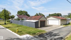 Two separate detached garages with pitched roofs, concrete driveways, and a private perimeter fence - 