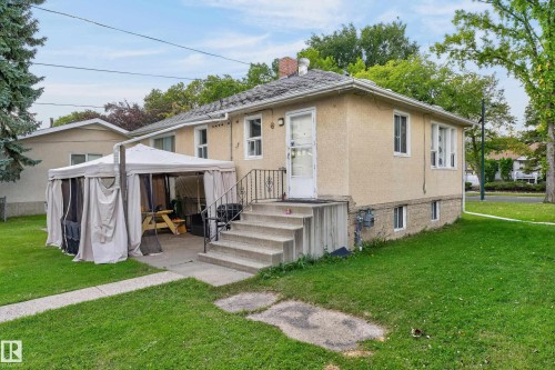 Stucco exterior with a side patio, concrete steps, and a lush green lawn - 12345 79 Street Nw, Edmonton, AB 