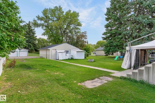 Expansive green lawn with mature trees and a detached garage featuring two roll-up doors - 12345 79 Street Nw, Edmonton, AB 
