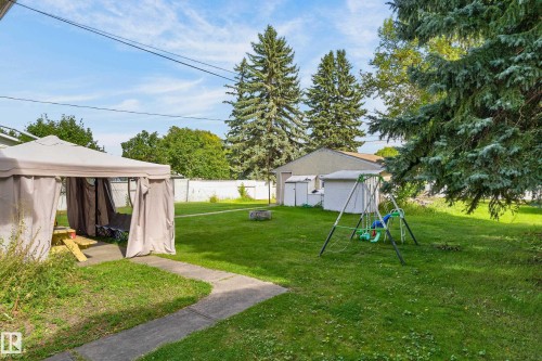 Expansive backyard featuring a manicured lawn, established perimeter trees, and a detached auxiliary structure - 12345 79 Street Nw, Edmonton, AB 