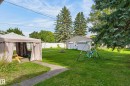 Expansive backyard featuring a manicured lawn, established perimeter trees, and a detached auxiliary structure - 12345 79 Street Nw, Edmonton, AB 