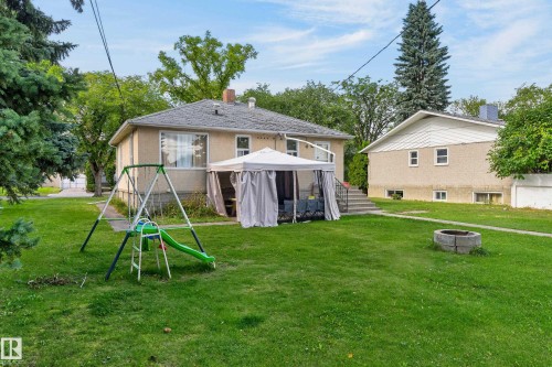 Expansive green lawn with mature trees, a stone fire pit, and concrete steps to the rear entry - 12345 79 Street Nw, Edmonton, AB 