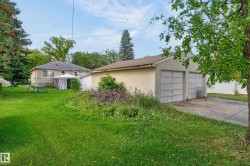 Detached two-car garage with panel doors, shingle roofing, and a concrete driveway - 