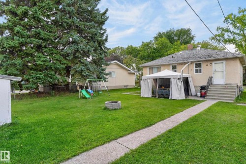 Spacious backyard featuring a manicured lawn, mature trees, and a concrete pathway - 12345 79 Street Nw, Edmonton, AB 