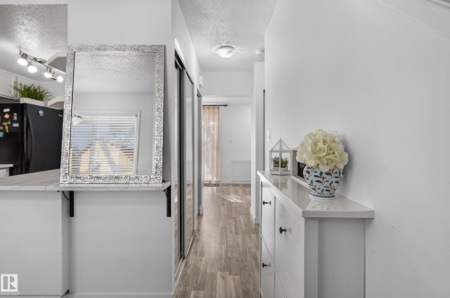 Wood-finish flooring throughout, white walls, and built-in hallway storage - 130 Woodstock Nw, Edmonton, AB 
