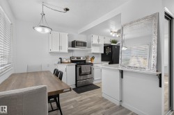 White cabinetry with brushed nickel hardware, stainless steel appliances, wood-finish flooring, recessed lighting, and a kitchen peninsula with a countertop - 