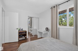 Wood-finish flooring, white walls, and a large window with exterior scenery - 