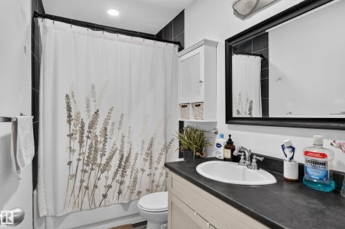 White vanity with a single basin sink, chrome faucet, and dark countertop - 130 Woodstock Nw, Edmonton, AB 