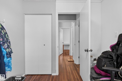 Wood-finish flooring throughout, white walls, and a white bi-fold closet door - 130 Woodstock Nw, Edmonton, AB 