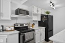 White cabinetry, stainless steel range, and light-toned countertops, complemented by a black refrigerator and track lighting - 130 Woodstock Nw, Edmonton, AB 