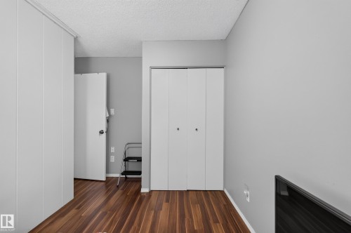 Wood-finish flooring with white baseboards, light grey wall paint, and bi-fold closet doors - 130 Woodstock Nw, Edmonton, AB 