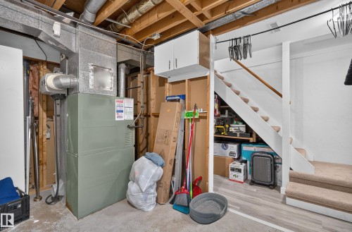 Carpeted staircase with wood handrail, under-stair storage, and overhead ductwork - 130 Woodstock Nw, Edmonton, AB 