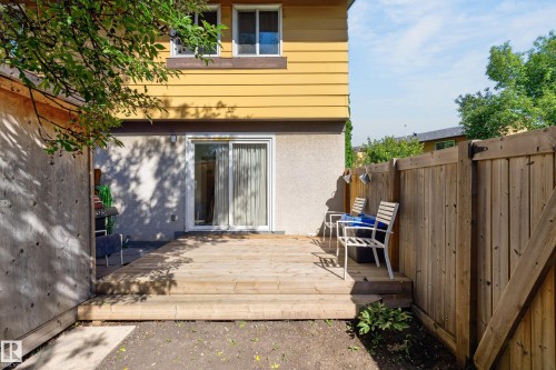 Raised wood deck, wood privacy fencing, sliding glass door, and yellow exterior siding - 130 Woodstock Nw, Edmonton, AB 