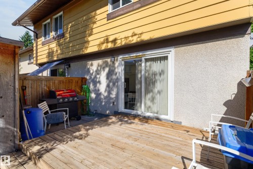 Expansive wood deck with a privacy fence, stucco exterior, and sliding glass door access - 130 Woodstock Nw, Edmonton, AB 