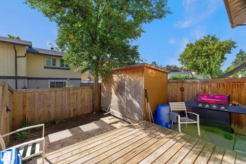 Private backyard featuring a wooden deck, a storage shed, and a wood-paneled fence - 130 Woodstock Nw, Edmonton, AB 