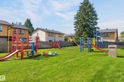 Expansive green space featuring multiple play structures with slides, a balance beam, and swings - 