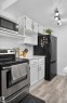 Stainless steel range, wood-finish flooring, white cabinetry with contemporary hardware, and track lighting - 130 Woodstock Nw, Edmonton, AB 
