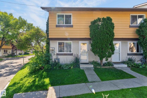 Two-story exterior with horizontal panel siding, ground floor entryways, and upper-level windows - 130 Woodstock Nw, Edmonton, AB 