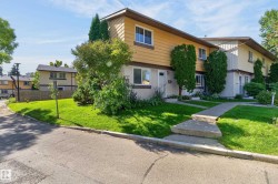 Duplex exterior with yellow siding and a partial brick facade, featuring a concrete walkway and a well-maintained lawn - 