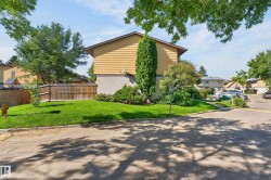 Yellow siding exterior with a pitched roof, mature landscaping, and a well-maintained lawn - 