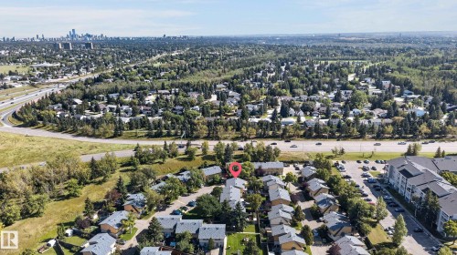 Aerial perspective of a residential community featuring mature trees and a distant city skyline - 130 Woodstock Nw, Edmonton, AB 