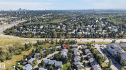 Aerial perspective of a residential community featuring mature trees and a distant city skyline - 