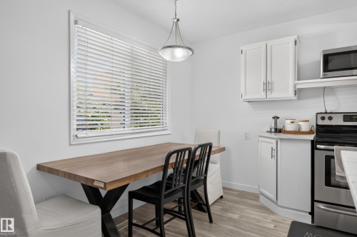 White cabinetry with chrome hardware, stainless steel appliances, and wood-finish flooring - 130 Woodstock Nw, Edmonton, AB 