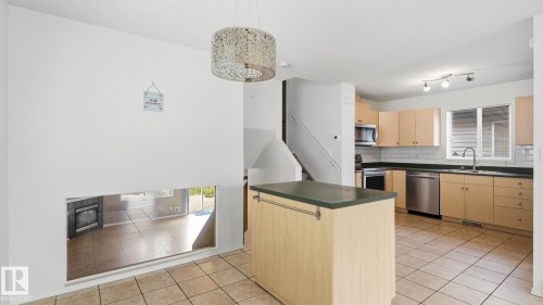 Kitchen with light wood-finish cabinetry, stainless steel appliances, a center island with a dark countertop, and tiled flooring - 2117 36 Avenue Nw, Edmonton, AB 