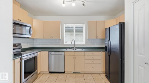 Kitchen with light-toned cabinetry, tile flooring, and a subway tile backsplash - 2117 36 Avenue Nw, Edmonton, AB 