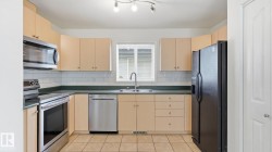 Kitchen with light-toned cabinetry, tile flooring, and a subway tile backsplash - 