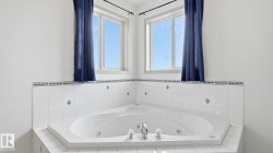 Corner jetted tub with white tile surround and decorative accents - 