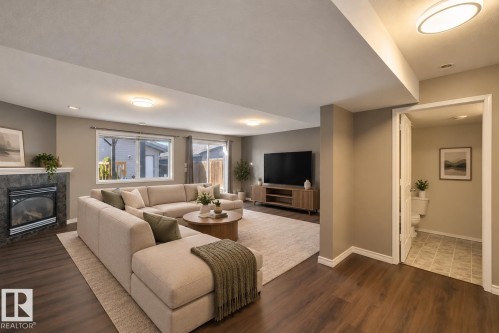 Spacious living area featuring wood-finish flooring, a fireplace with a stone surround, and recessed lighting - 2117 36 Avenue Nw, Edmonton, AB 