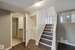 Wood-finish flooring, staircase with white risers, glass panel railing, and built-in vanity with countertop - 