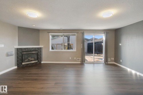 Wood-finish flooring, corner fireplace with tile surround, sliding glass door, recessed lighting, and a transom window - 2117 36 Avenue Nw, Edmonton, AB 