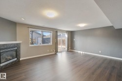 Living area featuring wood-finish flooring, a fireplace with a tiled surround and mantel, and a sliding glass door - 