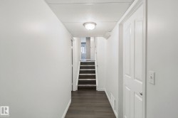 Hallway featuring dark wood-finish flooring, light-toned walls, a flush-mount ceiling light, and a paneled interior door - 