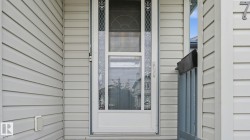 Front entry with decorative glass storm door and light-toned horizontal siding - 