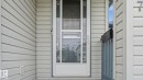 Front entry with decorative glass storm door and light-toned horizontal siding - 2117 36 Avenue Nw, Edmonton, AB 