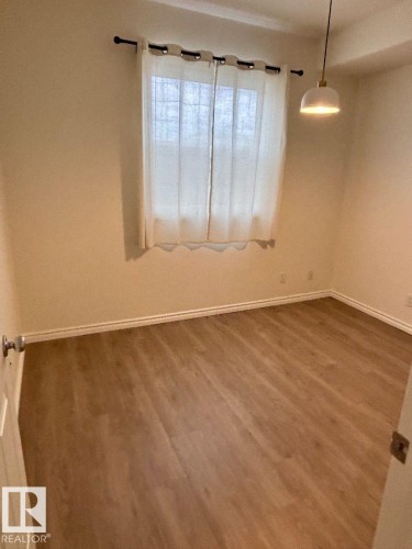 Wood-finish flooring, neutral wall tones, and a window with natural light - #103 10346 117 St Nw, Edmonton, AB 
