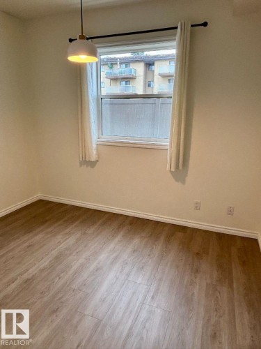 Wood-finish flooring with light-toned walls and a single window - #103 10346 117 St Nw, Edmonton, AB 