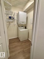 Dedicated laundry area with wood-finish flooring, white walls, and built-in wire shelving - 