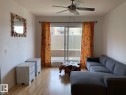 Wood-finish flooring throughout, ceiling fan with integrated lighting, and sliding glass door access to a private patio - #103 10346 117 St Nw, Edmonton, AB 