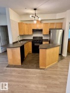 U-shaped kitchen featuring wood-finish cabinetry, dark countertops, and stainless steel refrigerator - 