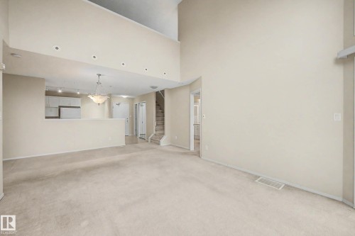 Two-story living area with high ceilings, recessed lighting, and neutral carpeting - #505 7839 96 St Nw, Edmonton, AB 