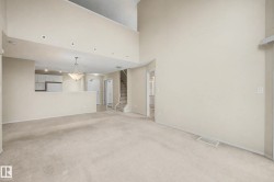 Two-story living area with high ceilings, recessed lighting, and neutral carpeting - 
