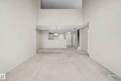 Soaring ceilings with recessed lighting, open loft area, kitchen passthrough with pendant lighting, and neutral carpeting throughout - 