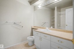 Bathroom featuring a vanity with a white basin sink, light-toned countertop, and white cabinetry with brass-finish hardware - 