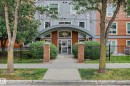 Building exterior featuring modern gray and wood-finish siding, arched entrance canopy, and brick pillars - #505 7839 96 St Nw, Edmonton, AB 