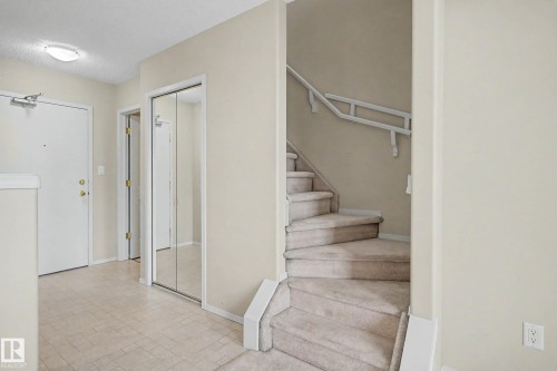 Carpeted staircase, mirrored closet doors, and light-toned flooring - #505 7839 96 St Nw, Edmonton, AB 