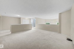 Carpeted open loft area with a partial wall, white sliding doors, and windows providing natural light - 